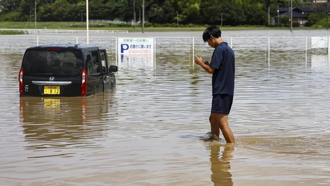 A local resident walks in a flooded area after heavy rain in Oamishirasato, Chiba Prefecture, Japan, August 14, 2026. REUTERS/Issei Kato