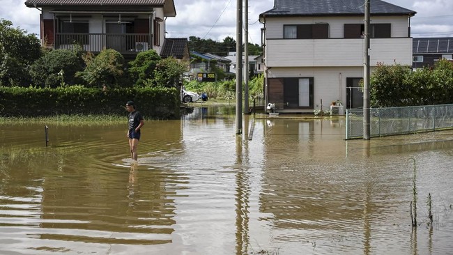 A local resident stands in a flooded area after heavy rain in Oamishirasato, Chiba Prefecture, Japan, August 14, 2026. REUTERS/Issei Kato