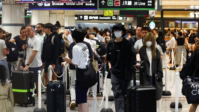 Passengers queue to enter the train station after train lines and public transportation services were suspended due to heavy rain at the Narita International Airport in Narita, Chiba prefecture, Japan August 14, 2026.   REUTERS/Issei Kato