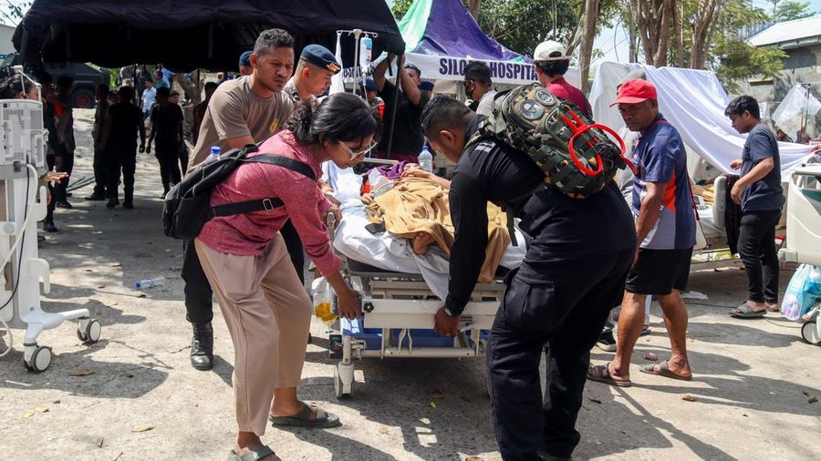 Petugas kepolisian membantu memindahkan seorang pasien ke tempat penampungan di area terbuka sebuah rumah sakit, menyusul gempa bumi nan terasa di Labuan Bajo, Provinsi Nusa Tenggara Timur, Indonesia, Minggu (15/8/2026). (REUTERS/Stringer)