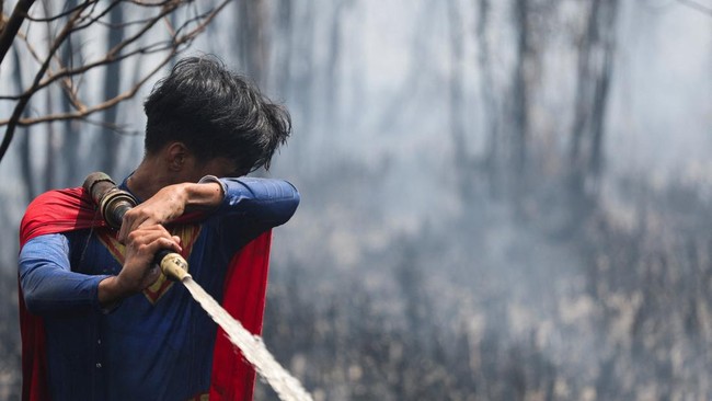 Rudiyansah, 16, wears a Superman costume, reacts while extinguishing a fire at a wildfire-affected area in Palangka Raya, Central Kalimantan province, Indonesia, August 14, 2026. REUTERS/Ajeng Dinar Ulfiana