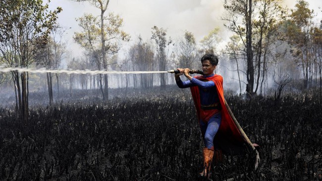 Rudiyansah, 16, wears a Superman costume while extinguishing a fire at a wildfire-affected area in Palangka Raya, Central Kalimantan province, Indonesia, August 14, 2026. REUTERS/Ajeng Dinar Ulfiana