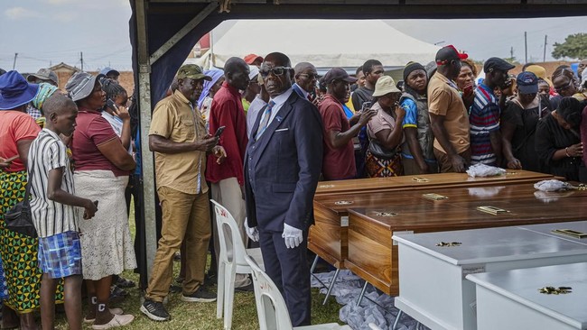 A pallbearer stands guard as mourners file past coffins during a memorial service held for victims of the capsized Rural Infrastructure Development Agency (RIDA) passenger ferry at Nyamhunga Stadium in Kariba, on August 13, 2026. A government passeng