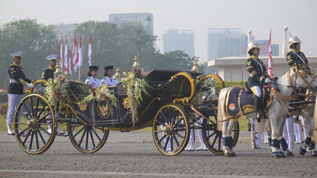 Purna Paskibraka Duta Pancasila 2025 Bianca Sultana Najwa (keempat kiri) dan Aliah Sakira (ketiga kiri) membawa bendera pusaka dan naskah Proklamasi di atas kereta kencana Garuda Prabayaksa dari Monumen Nasional menuju Istana Merdeka dalam kirab Mera