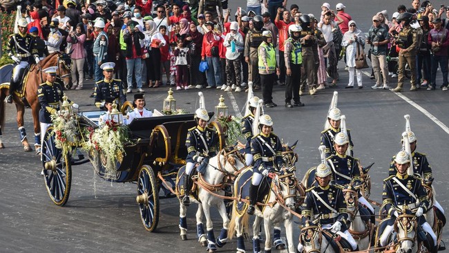 Purna Paskibraka Duta Pancasila 2025 Bianca Sultana Najwa (kanan) dan Aliah Sakira (kiri) membawa bendera pusaka dan naskah Proklamasi di atas kereta kencana Garuda Prabayaksa dari Monumen Nasional menuju Istana Merdeka dalam Kirab Merah Putih di Jak