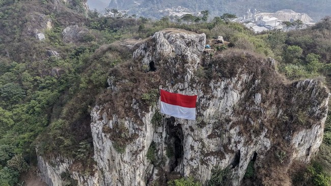 Foto udara pegiat panjat tebing dari Komunitas Tebing Hawu Pabeasan mengibarkan bendera Merah Putih raksasa di Tebing Hawu, Padalarang, Kabupaten Bandung Barat, Jawa Barat, Senin (17/8/2026). Upacara dan pengibaran bendera raksasa di kawasan tebing h