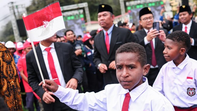 Seorang anak mengibarkan Bendera Merah Putih usai upacara HUT ke-81 Kemerdekaan RI di Sporthall Tembagapura, Mimika, Papua, Senin (17/8/2026). PTFI menggelar upacara secara serentak yang diikuti 2.281 peserta di Tembagapura, Kuala Kencana, Nabire, Gr