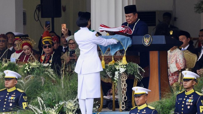 Indonesian President Prabowo Subianto holds the national flag carried by a flag bearer during a flag-raising ceremony marking the country's 81st Independence Day, at the Presidential Palace in Jakarta, Indonesia, August 17, 2026. REUTERS/Ajeng Dinar