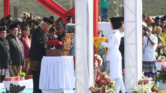Kepala Otorita Ibu Kota Nusantara Basuki Hadimuljono (kiri) menyerahkan bendera kepada Tim Delapan Pengibar Bendera, Khalizqa Refqi Ramadhani (kanan) saat upacara peringatan HUT Kemerdekaan ke-81 RI di Lapangan Plaza Seremoni, Ibu Kota Nusantara, Kal