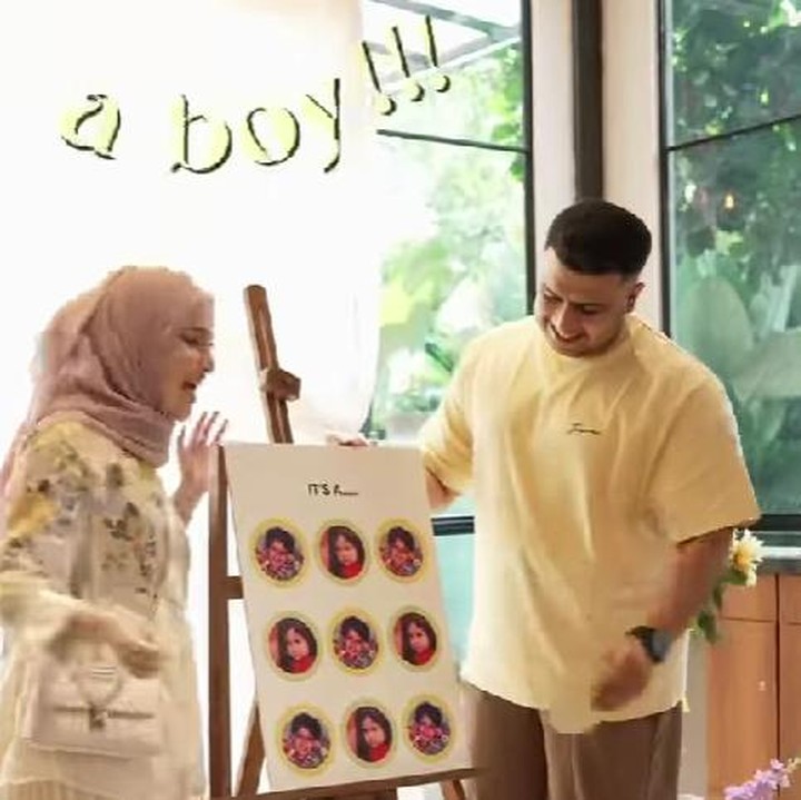 <p>Miskah dan Yislam terlihat berdiri di depan papan gender reveal yang berisi sejumlah foto masa kecil mereka berdua. Mereka membuka satu persatu foto sampai yang terkhir foto Yislam kecil, menandakan anak kedua mereka laki-laki. (Foto:instagram @miskashf)</p>