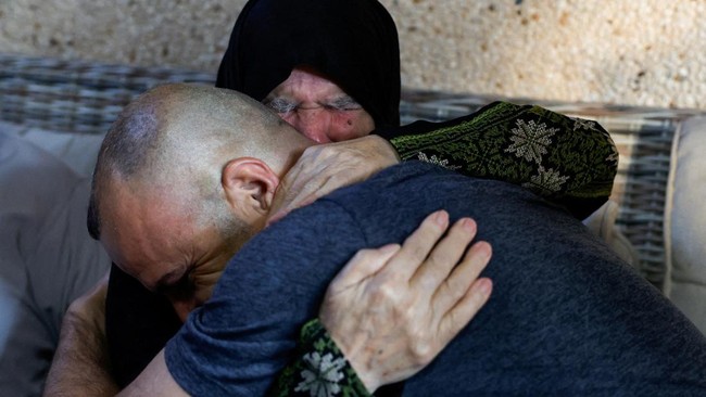 Palestinian-American Loui Ridi, who seeks access to his home in the Israeli-occupied West Bank that has been encircled by militant settlers for more than a week, embraces his mother at her home, in Qusra village, Israeli-occupied West Bank, August 17