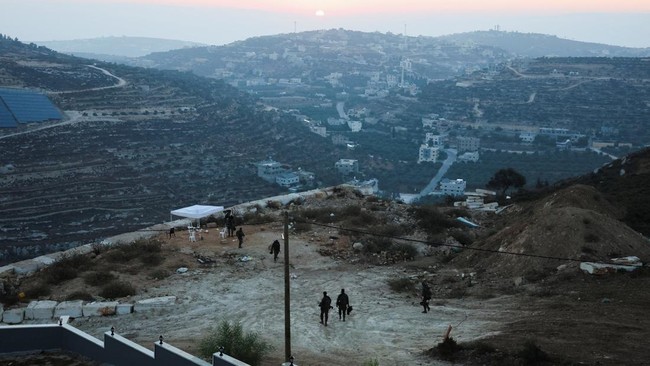 Israeli soldiers walk near the home of Palestinian-American Loui Ridi, which has been encircled by militant settlers for more than a week, after Ridi gained access to it, in Qusra, Israeli-occupied West Bank, August 18, 2026. REUTERS/Ammar Awad