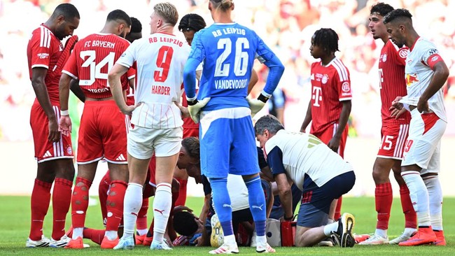 Soccer Football - Pre Season Friendly - Bayern Munich v RB Leipzig - Allianz Arena, Munich, Germany - August 15, 2026 Bayern Munich's Jamal Musiala receives medical attention after sustaining an injury as players look on REUTERS/Angelika Warmuth