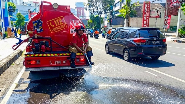 Petugas Damkar Surabaya mengguyur jalan untuk mengurangi risiko panas ekstrem saat musim kemarau.