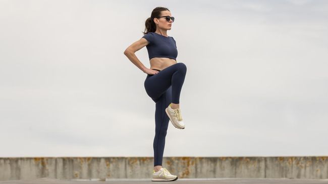 Sporty woman stretching leg muscles with standing single knee to chest stretch