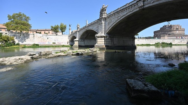 This photograph shows an Ancient Roman bridge emerging from the Tiber River, near the Castel Sant'Angelo (R), in central Rome on 13 August, 2026. The unusually low waters of the Tiber River have revealed the remains of an ancient Roman bridge believe