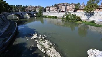 This photograph shows an Ancient Roman bridge emerging from the Tiber River, near the St. Peter Doome's Basilica at the Vatican City (R), in central Rome on 13 August, 2026. The unusually low waters of the Tiber River have revealed the remains of an
