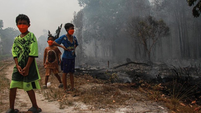 Sejumlah anak melihat kebakaran lahan yang mendekati permukiman warga di Kelurahan Sabaru, Palangka Raya, Kalimantan Tengah, Sabtu (15/8/2026). Petugas gabungan bersama warga setempat memadamkan kebakaran lahan yang mendekati kawasan permukiman denga