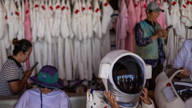 A boy puts on an astronaut helmet inside a rental shop at Volcano No. 6 of the Wulanhada Volcano Geopark in Ulanqab, Inner Mongolia Autonomous Region, China, July 26, 2026. In China's northern region of Inner Mongolia, black volcanic rock formations