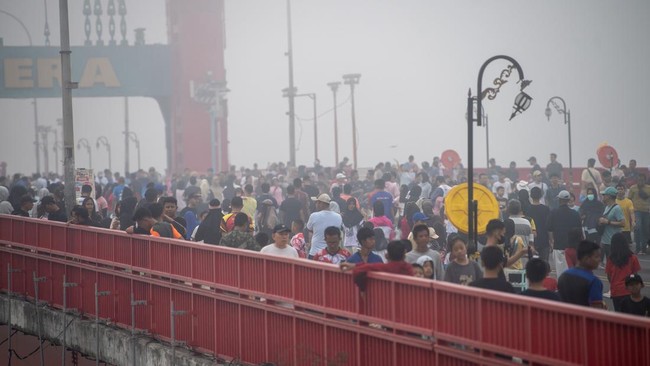 Sejumlah warga berolahraga di atas Jembatan Ampera yang tertutup kabut asap saat pelaksanaan hari bebas kendaraan bermotor (HBKB) di Kota Palembang, Sumatera Selatan, Minggu (23/8/2026). Berdasarkan citra satelit Himawari-9 yang dipantau BMKG pada Mi