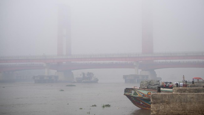 Warga berada di atas perahu tradisional dengan latar belakang jembatan Ampera Palembang yang tertutup kabut asap di kawasan 16 ilir Palembang, Sumatera Selatan, Minggu (23/8/2026). Berdasarkan citra satelit Himawari-9 yang dipantau BMKG pada Minggu (