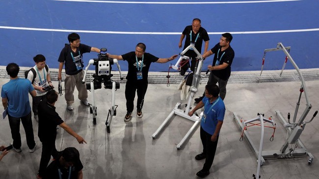Staff members help to direct a Tiangong Ultra humanoid robot following a 400m large-size group preliminary race, during the second World Humanoid Robot Games at the National Speed Skating Oval in Beijing, China August 22, 2026. REUTERS/Florence Lo
