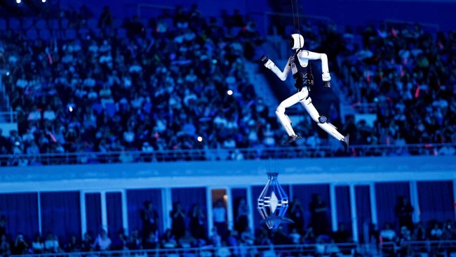 A humanoid robot walks in the air while on strings near a Chinese national flag during the opening ceremony of the World Humanoid Robot Games 2026 at the National Speed Skating Oval stadium, in Beijing, China August 22, 2026. REUTERS/Tingshu Wang