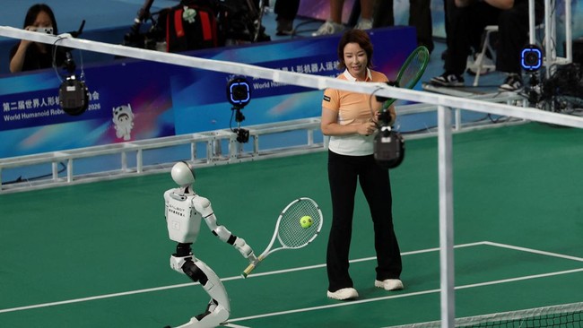 A Galbot humanoid robot takes part in a tennis exhibition match alongside Chinese former tennis player Zheng Jie during the opening ceremony for the second World Humanoid Robot Games at the National Speed Skating Oval in Beijing, China August 22, 202