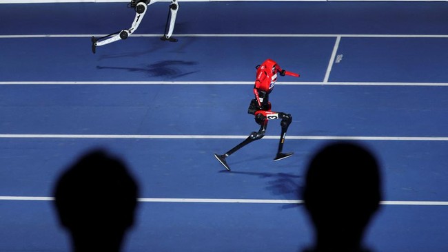 Spectators watch as a Lightning humanoid robot by Honor and a Tiangong Ultra humanoid robot compete in a 100m exhibition race during the opening ceremony for the second World Humanoid Robot Games at the National Speed Skating Oval in Beijing, China A