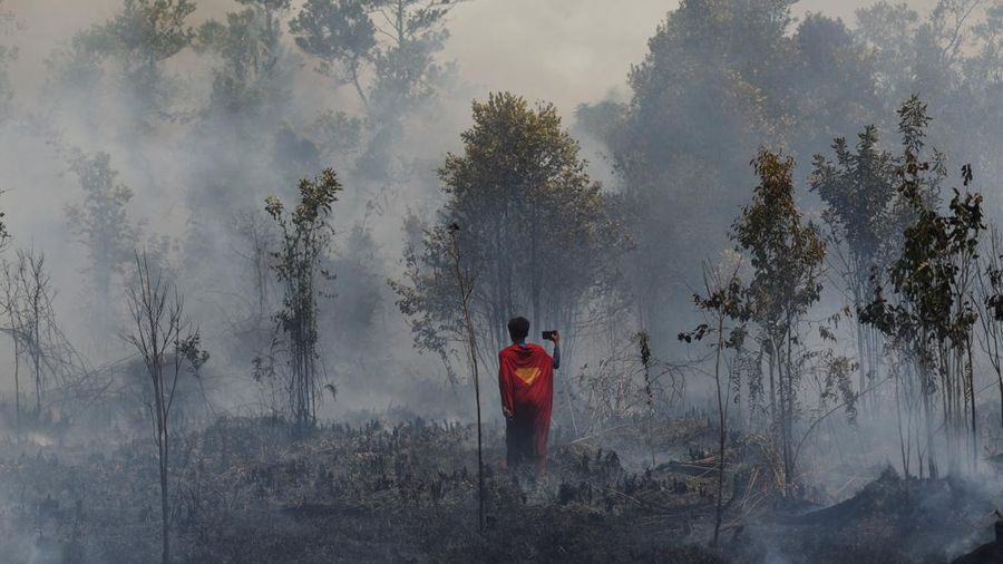 Rudiyansah, 16 tahun, mengenakan kostum Superman saat memadamkan api di area nan terdampak kebakaran rimba dan lahan di Palangka Raya, Provinsi Kalimantan Tengah, Jumat (14/8/2026). (REUTERS/Ajeng Dinar Ulfiana)