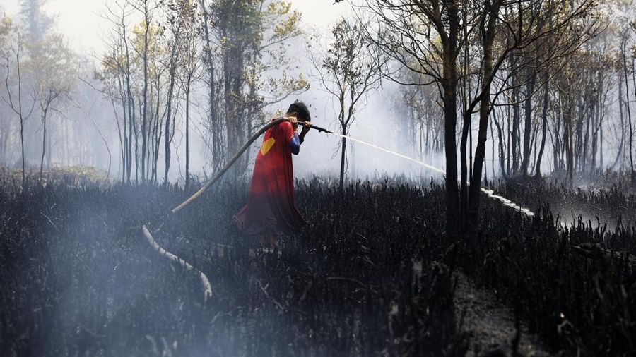 Rudiyansah, 16 tahun, mengenakan kostum Superman saat memadamkan api di area nan terdampak kebakaran rimba dan lahan di Palangka Raya, Provinsi Kalimantan Tengah, Jumat (14/8/2026). (REUTERS/Ajeng Dinar Ulfiana)