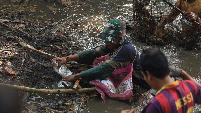 Seorang warga berhasil menangkap ikan saat tradisi Grobyak Ikan di Sumber Gundi, Kabupaten Kediri, Jawa Timur, Minggu (23/8/2026). Tradisi memanen ikan hanya sekali dalam setahun tersebut merupakan cara warga sekitar mensyukuri aliran mata air yang t