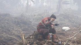 Personel Manggala Agni Daops Pekanbaru yang kelelahan membasuh muka dengan air saat berupaya melakukan pemadaman lahan yang terbakar.