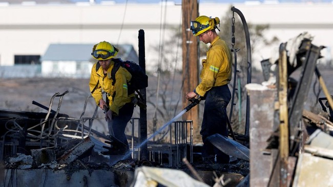 Two firefighters knock down hotspots in the charred remains of a home burned in the Hawk Fire in Reno, Nevada, U.S., August 24, 2026. REUTERS/Fred Greaves