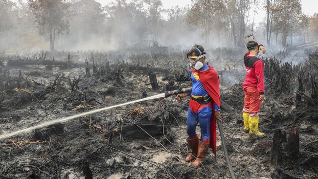 Pakai kostum Superman, seorang remaja bernama Rudiyansah menunjukkan semangat dengan ikut memadamkan karhutla di lahan gambut Palangkaraya.