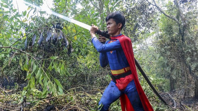Pakai kostum Superman, seorang remaja bernama Rudiyansah menunjukkan semangat dengan ikut memadamkan karhutla di lahan gambut Palangkaraya.