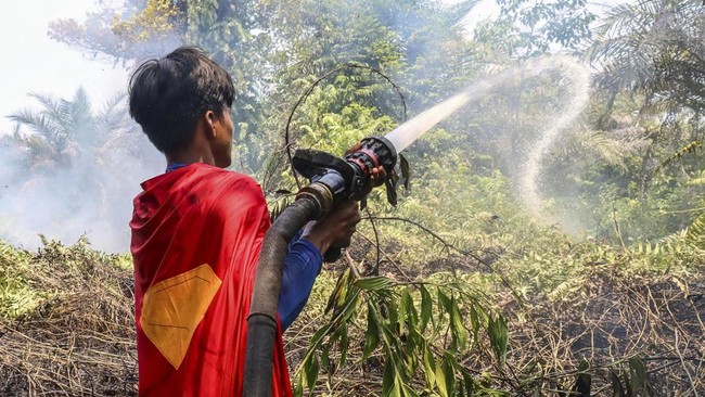 Pakai kostum Superman, seorang remaja bernama Rudiyansah menunjukkan semangat dengan ikut memadamkan karhutla di lahan gambut Palangkaraya.