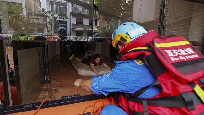 Rescue workers reach out to evacuate a resident stranded by floodwaters after heavy rainfall brought by typhoon Narra caused flooding in Ningming county, Chongzuo, Guangxi Zhuang Autonomous Region, China August 24, 2026. cnsphoto via REUTERS   ATTENT