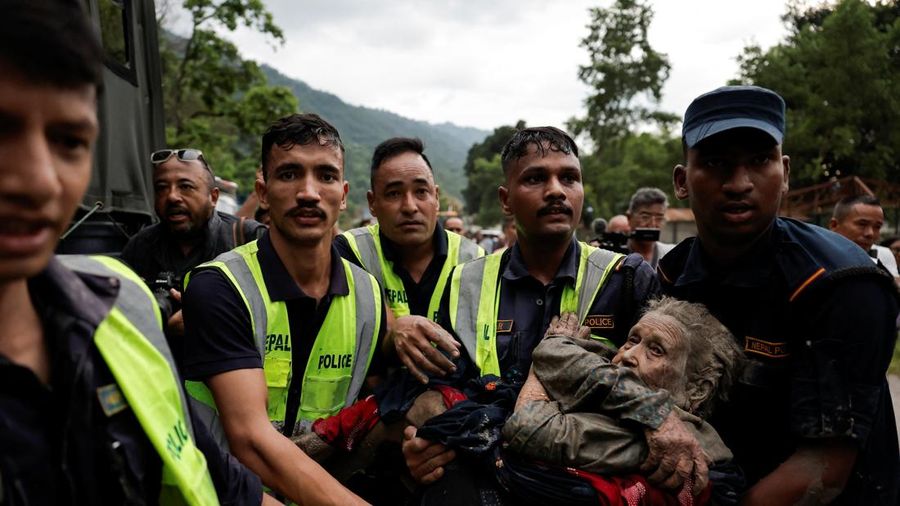Petugas kepolisian membawa seorang korban selamat ke tempat nan lebih kondusif setelah banjir bandang di Trishuli, distrik Nuwakot, Nepal, pada 26 Agustus 2026.
