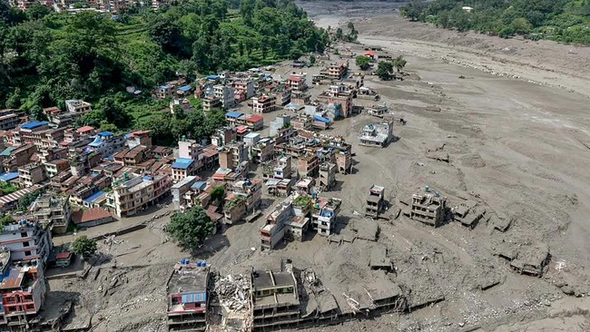 Houses lie partially submerged in muddy water along a riverside after flash floods at Trishuli Bazar in Nepal's Nuwakot district on August 26, 2026. A massive flood swept through Nepal's northern Rasuwa district on August 26, damaging roads and power