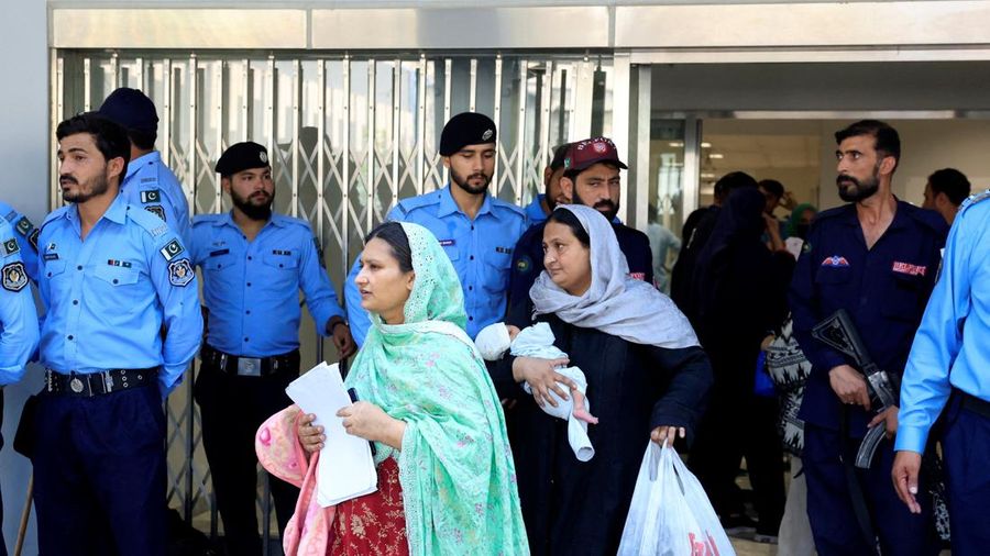 Seorang wanita nan menggendong bayi melintas di dekat petugas kepolisian saat meninggalkan bangsal usai kebakaran maut di rumah sakit Pakistan Institute of Medical Sciences (PIMS) di Islamabad, Pakistan, pada 26 Agustus 2026.
