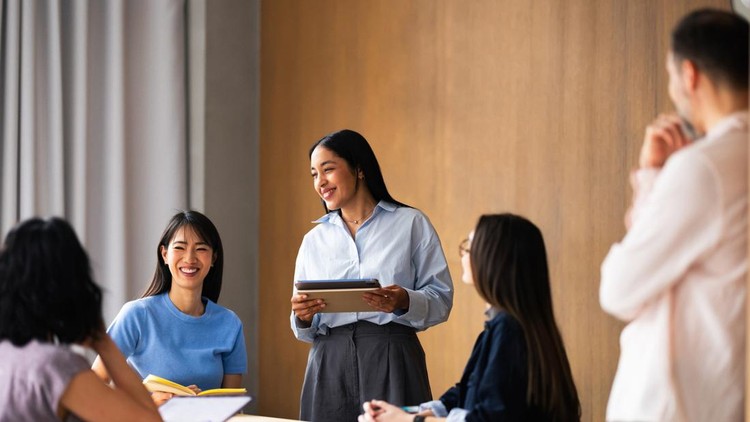A diverse group of colleagues laugh and collaborate as a female leader presents ideas with a tablet&period;