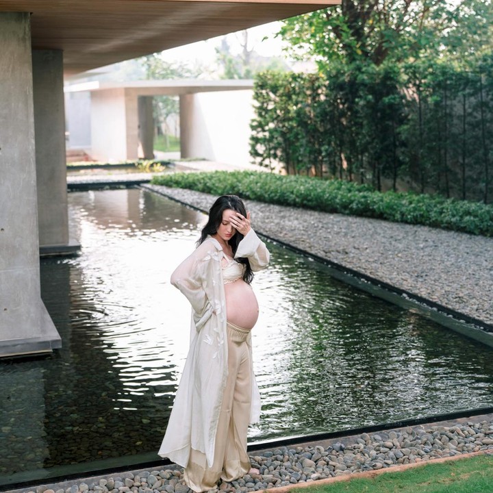 <p>Dalam satu potret, Julie tampil mengenakan <em>sheer duster cardigan</em> longgar berwarna putih, yang dipadukan dengan celana panjang warna krem. Gaya <em>casual</em> elegan ini terlihat begitu sempurna dengan latar pemandangan kolam yang dikelilingi dedaunan dan pepohonan hijau. (Foto: Instagram @julstelle)</p>