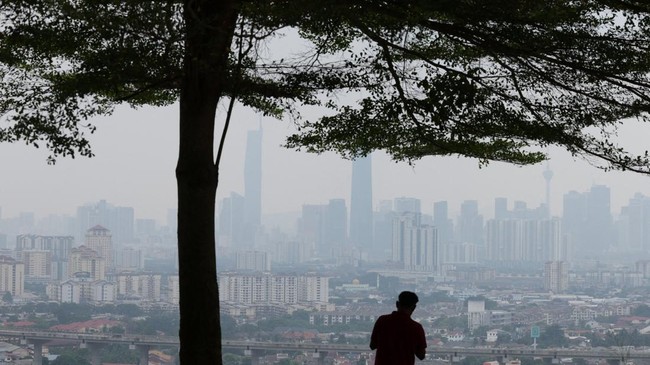 A man looks at Kuala Lumpur's skyline shrouded in haze from regional wildfires, as seen from Ampang, Malaysia, August 26, 2026. REUTERS/Hasnoor Hussain