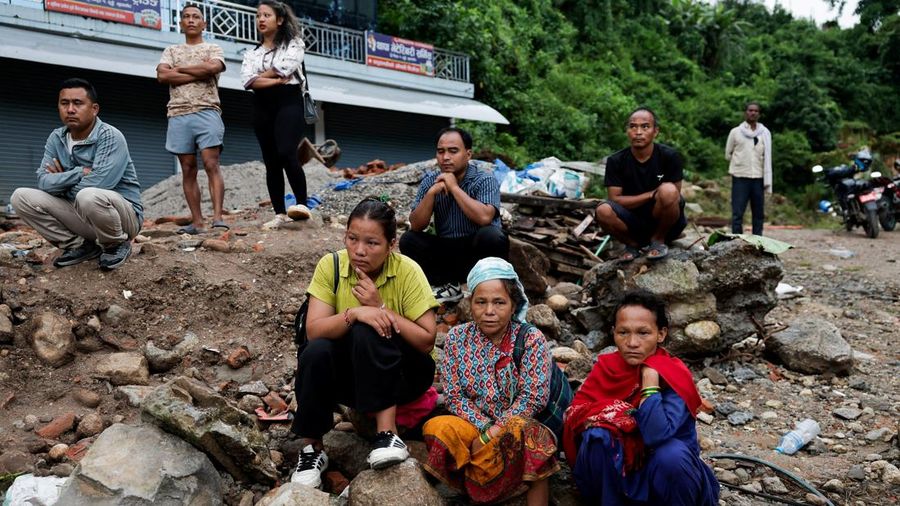 Para penyintas duduk di atas puing-puing sembari menunggu akses jalan menuju rumah mereka kembali terbuka setelah banjir luar biasa di Trishuli, Distrik Nuwakot, Nepal, pada 27 Agustus 2026.