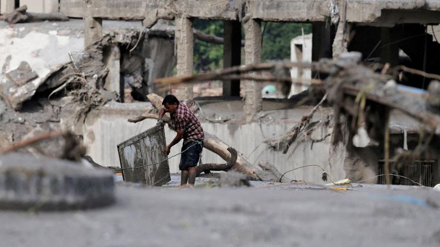 Seorang laki-laki menyelamatkan barang-barangnya dari lumpur setelah banjir luar biasa di Trishuli, Distrik Nuwakot, Nepal, pada 27 Agustus 2026.