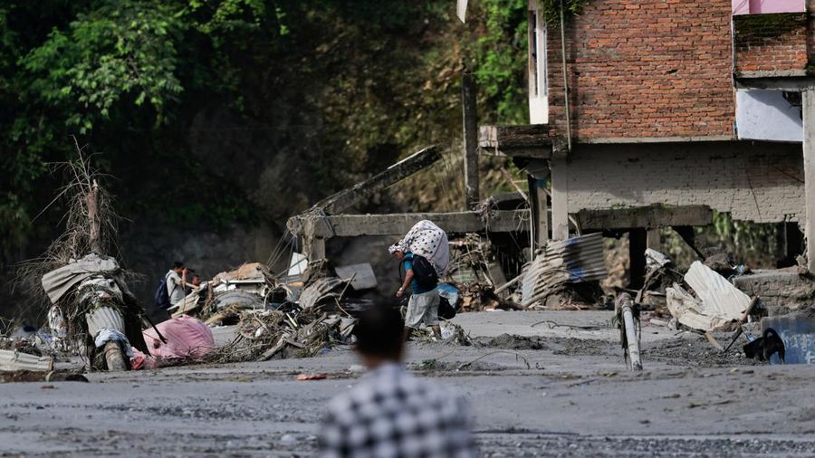 Seorang laki-laki nan membawa barang-barangnya melangkah melintasi puing-puing pascabanjir luar biasa di Trishuli, Distrik Nuwakot, Nepal, pada 27 Agustus 2026.