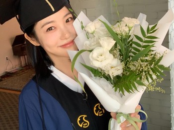Dalam postingan tersebut, Shin Ye Eun tampil menawan dengan toga wisuda lengkap sambil memegang kue dan buket bunga./ Foto: instagram.com/__shinyeeun