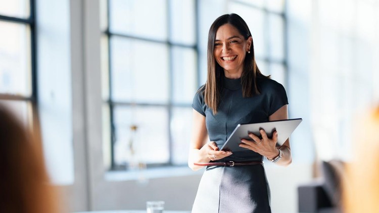 Smiling professional woman presenting in an office environment&comma; holding a tablet&comma; showcasing confidence and expertise&period; The natural lighting and supportive atmosphere highlight teamwork and career-oriented aspirations&period;