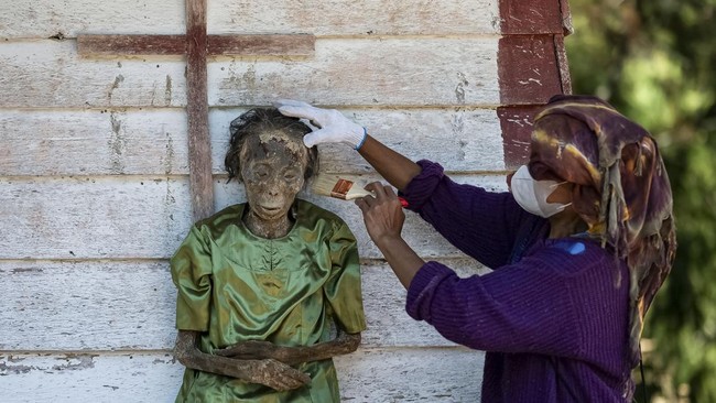 A relative cleans the remains of Sanda after they were removed from the burial chamber during Ma'nene, a Torajan ritual where families exhume, clean and redress their deceased relatives to honour them, in Pangala, North Toraja, South Sulawesi provinc
